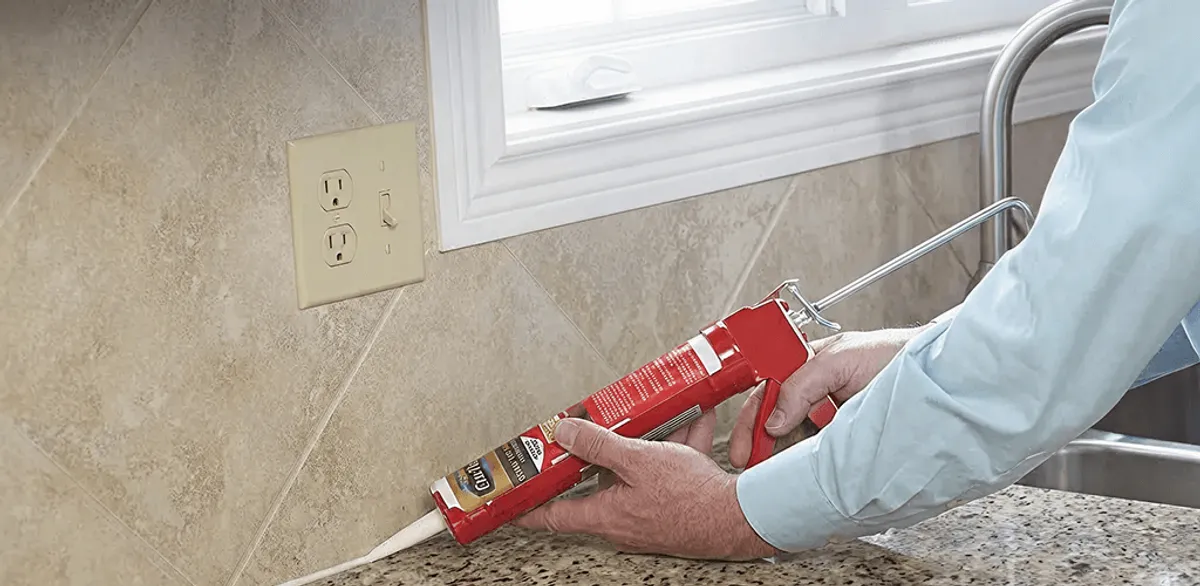 Handyman applying caulk along a kitchen backsplash and countertop seam in Tucson, AZ